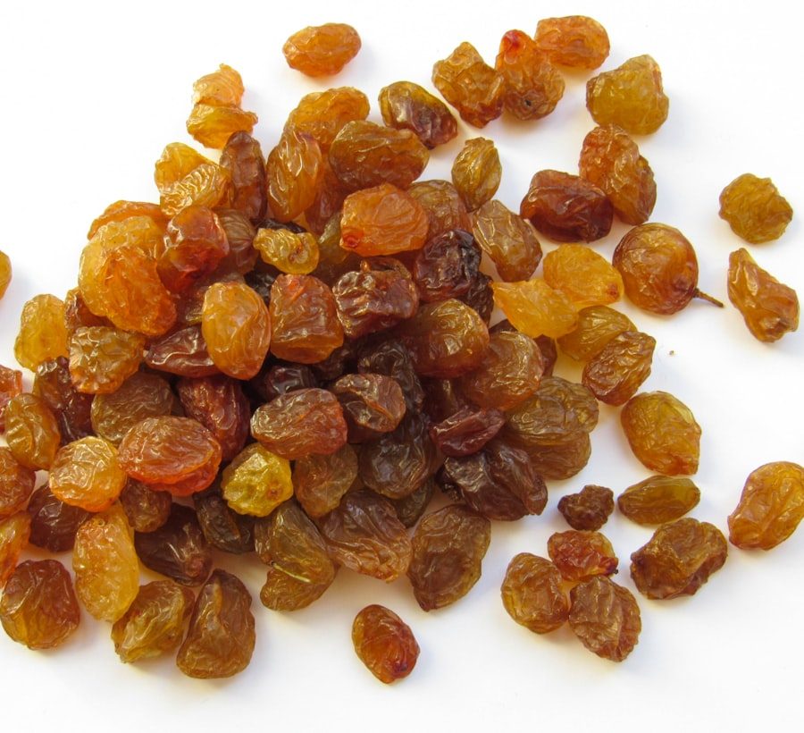 Golden raisins on a white surface